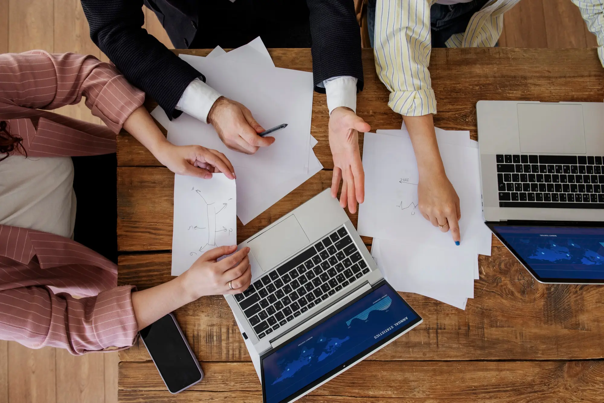 Team di lavoro che analizza documenti e dati attorno a un tavolo con laptop