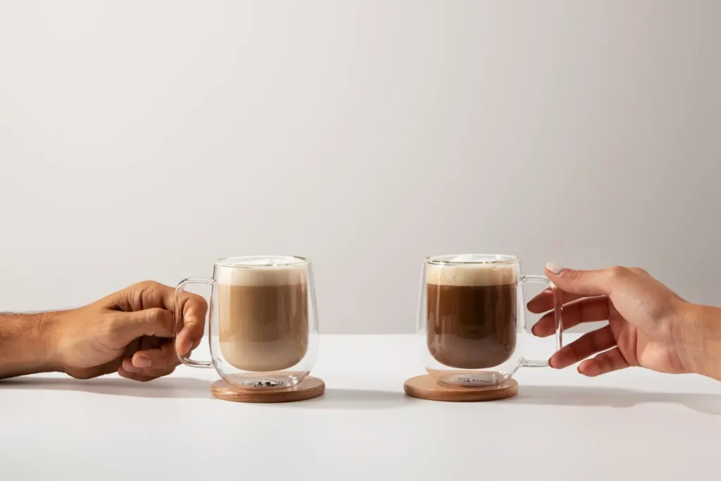 Due mani tengono bicchieri di caffè su lati opposti del tavolo — metafora del disallineamento tra marketing e vendite nelle PMI